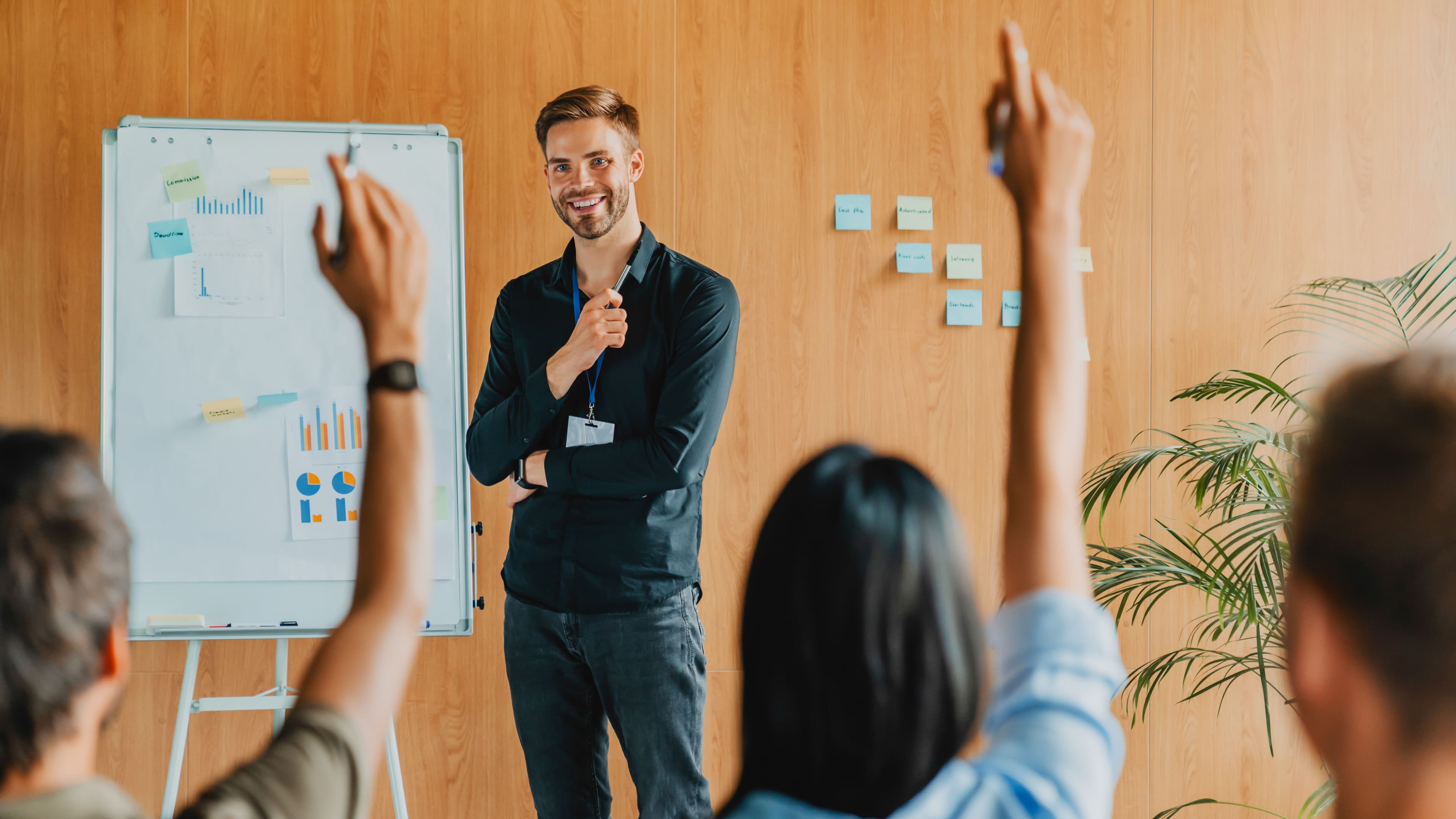 Man standing at the front of a room and smiling while training other teachers