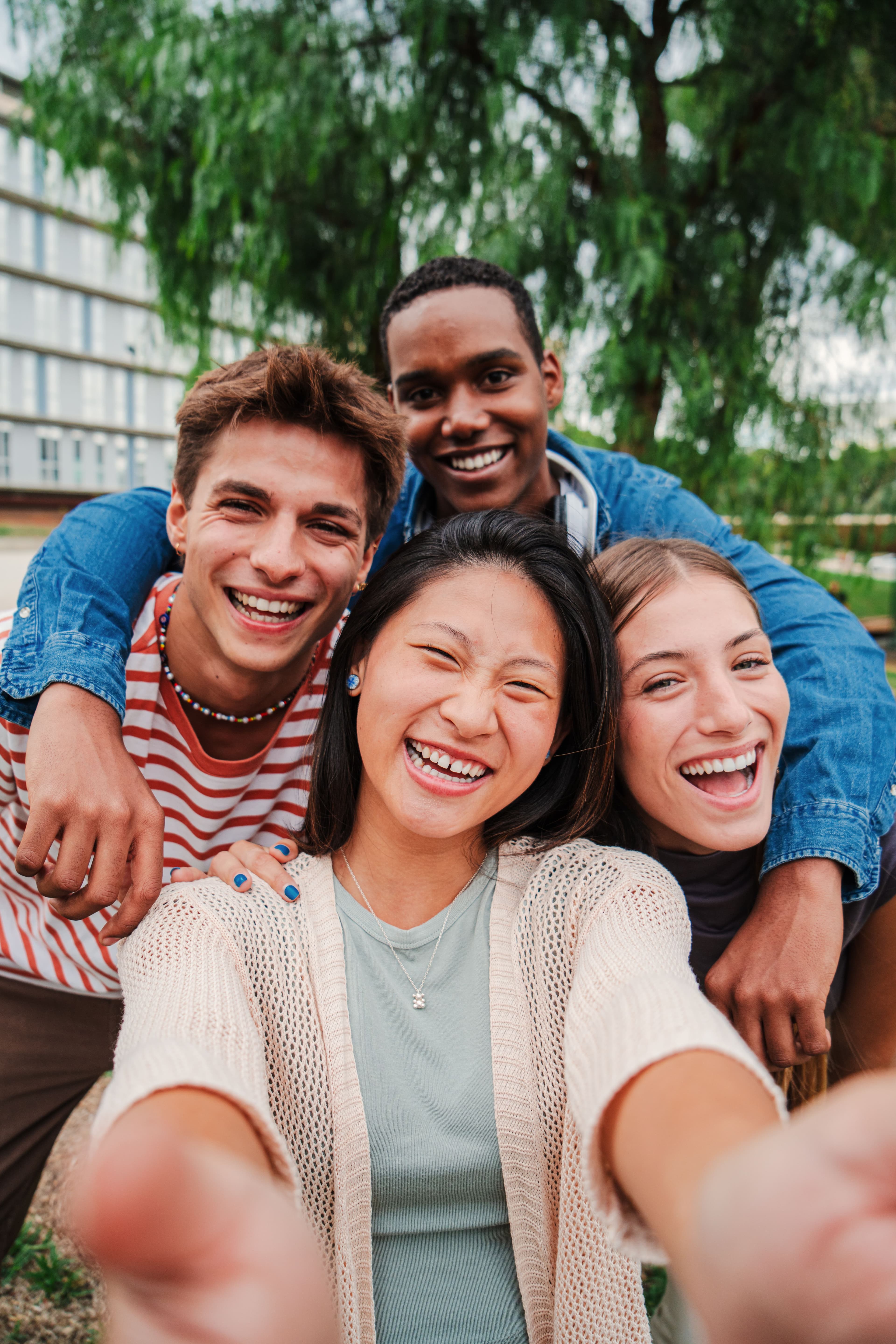 A group of young people smiling at the camera and taking a selfie